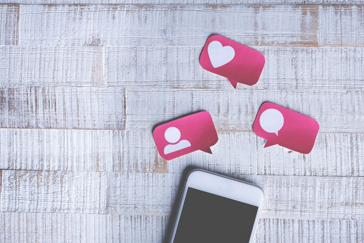 Smartphone displaying colorful social media app icons on a wooden desk