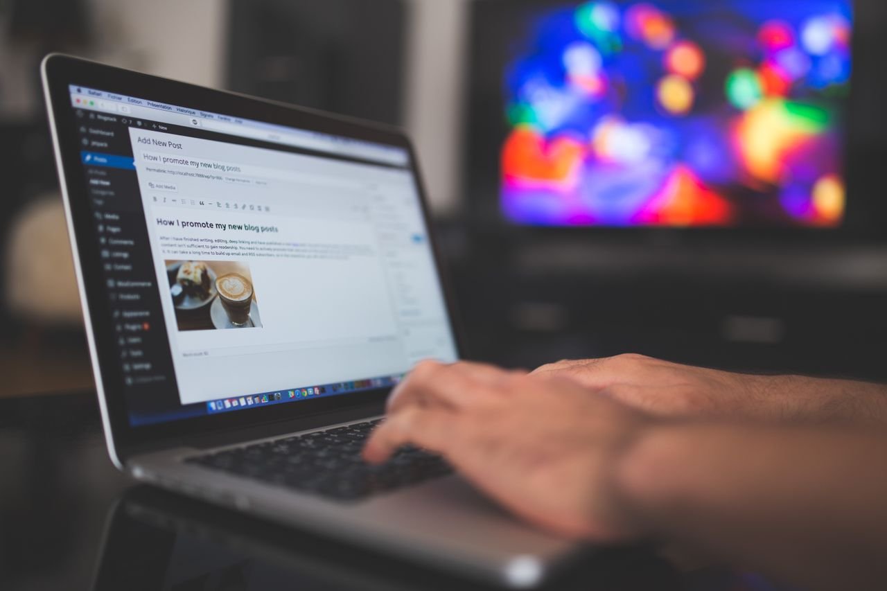 Person typing on a laptop next to a notebook and coffee cup