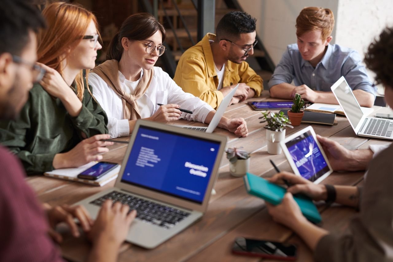 Team working around a table with laptops and tablets during a planning session
