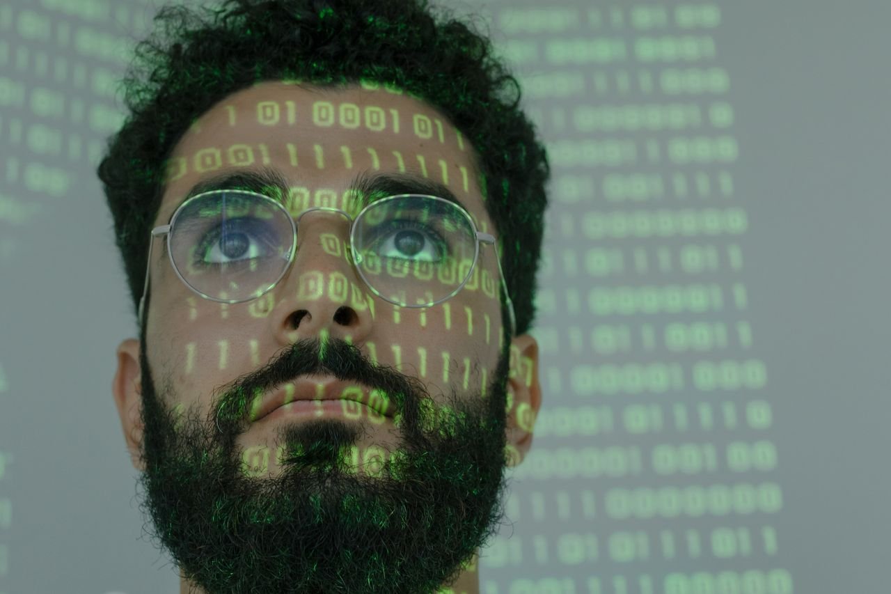 Man's face lit by projected green binary code