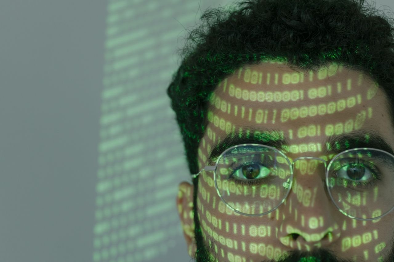 Close-up of a face lit by projected green binary code