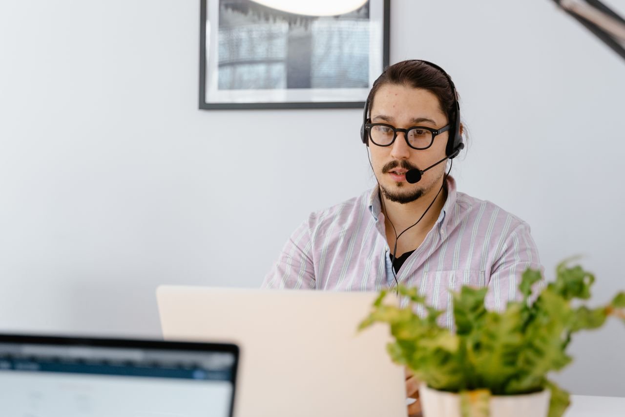 Support agent wearing a headset answering customer chats on a laptop
